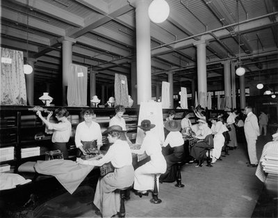 Interieur van stoffenwinkel. Stoffen meten en knippen voor klanten door W.C. Persons
